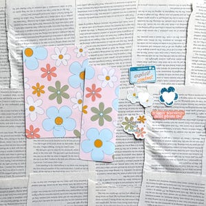 May include: Two pink and blue floral patterned cards with white daisies, orange and green flowers. The cards are surrounded by various stickers with text including "explicit content", "next week", and "trigger warning don't phase me".