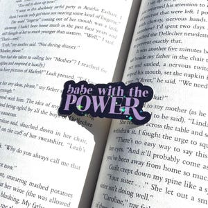 May include: A purple and black sticker with glitter accents. The sticker says "babe with the power" in bold white letters.