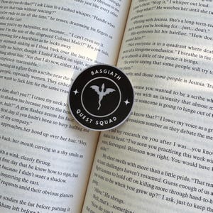 May include: Black and white sticker with a dragon silhouette and the text "Basgiath Quest Squad".