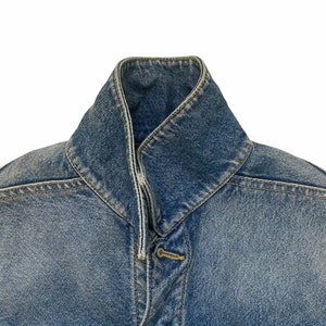 May include: A blue denim jacket with a pointed collar and a button closure.
