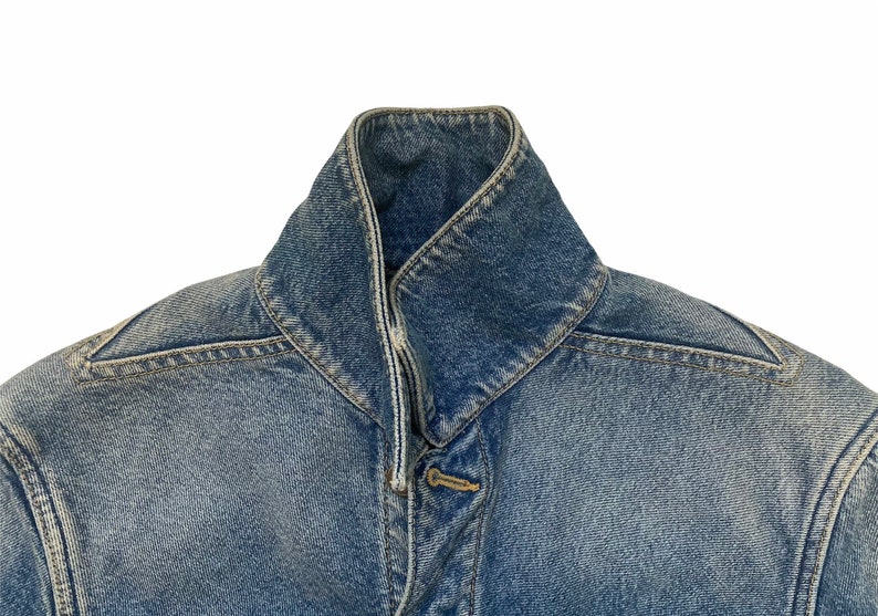 May include: A blue denim jacket with a pointed collar and a button closure.