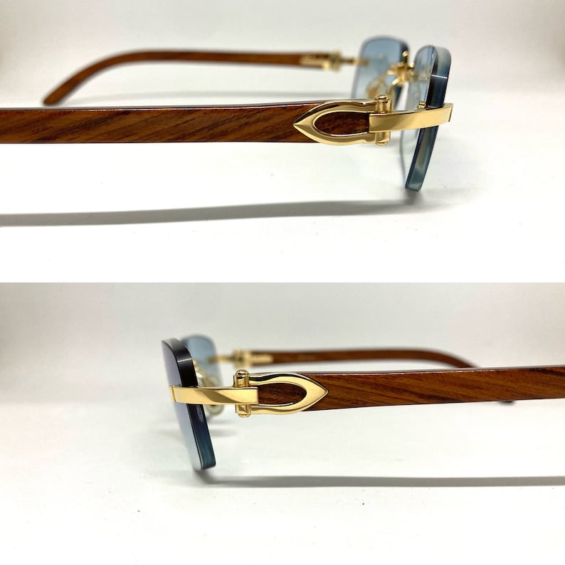 May include: A pair of sunglasses with a wooden frame and gold accents. The lenses are a light blue color.