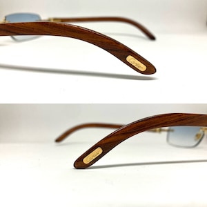 May include: A pair of brown wood-framed sunglasses with blue lenses. The sunglasses have a gold Cartier logo on the side of the frame.