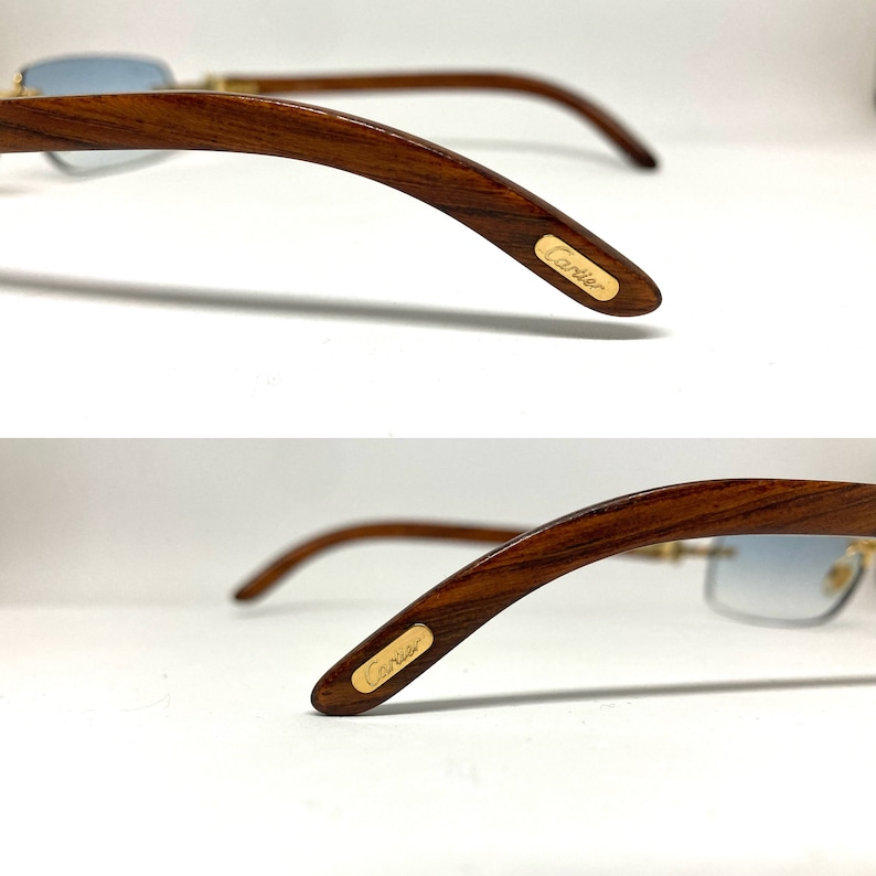 May include: A pair of brown wood-framed sunglasses with blue lenses. The sunglasses have a gold Cartier logo on the side of the frame.