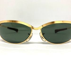 May include: Gold-tone sunglasses with a cat-eye frame and dark green lenses.