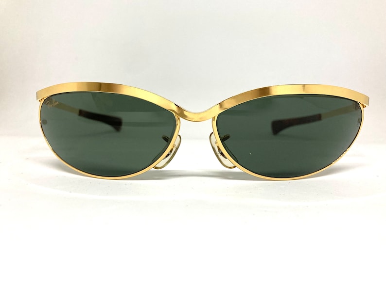 May include: Gold-tone sunglasses with a cat-eye frame and dark green lenses.