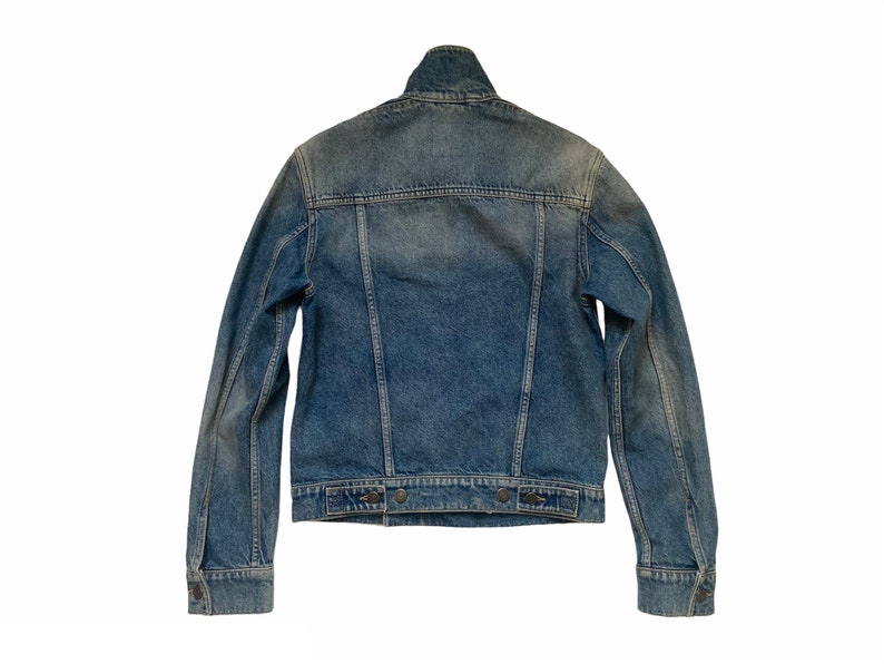 May include: A blue denim jacket with a classic design. The jacket has a button-up front, two chest pockets, and two front pockets.