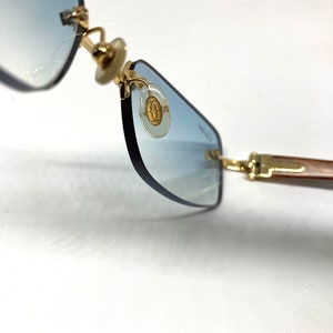 May include: Gold-tone sunglasses with blue tinted lenses and a gold logo on the side.