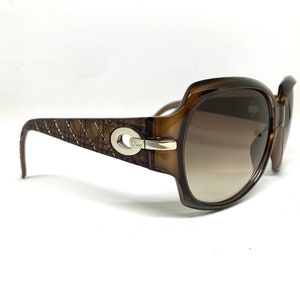 May include: Brown plastic sunglasses with a brown gradient lens and a silver Dior logo on the side.