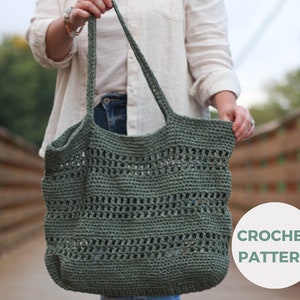 Puede incluir: Una bolsa de mano de crochet verde con una parte superior ancha y abierta y un patrón tejido. La bolsa está siendo sostenida por una persona, y el texto "CROCHET PATTERN" es visible en la esquina inferior derecha de la imagen.