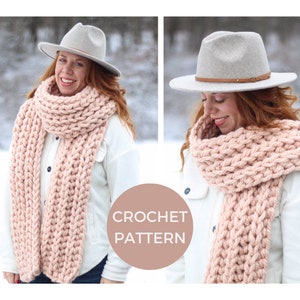 May include: A pink crochet scarf with a chunky knit texture. The scarf is worn by a person wearing a white shirt and a grey fedora.