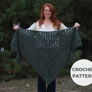 May include: A green crochet shawl with a lacy pattern and tassels. The shawl is draped over a person's shoulders. CROCHET PATTERN is written in white text on a gray circle.