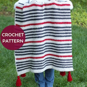 May include: A crochet blanket with red, white, and gray stripes and tassels. The blanket is held by a person in front of a green grassy background. The text "CROCHET PATTERN" is visible in a red circle.