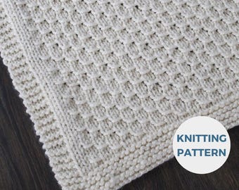 May include: A white knitted blanket with a textured stitch pattern. The blanket has a simple border and the words "Knitting Pattern" are visible in the bottom right corner.