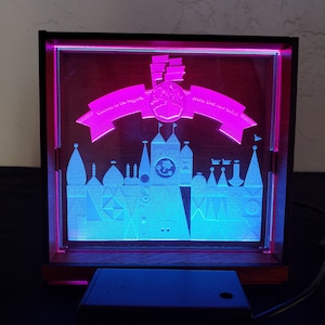 May include: A light-up display of the Cinderella Castle silhouette with the text "Welcome to the Magic" and "Dream the Impossible" on banners above the castle.