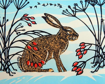 May include: A print of a hare in a winter scene. The hare is brown and tan, with long ears and is surrounded by black plant silhouettes and red berries. The background is light blue with a flock of birds.
