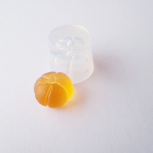 May include: A clear silicone mold for making small pumpkin-shaped resin crafts. A finished pumpkin-shaped resin piece is shown next to the mold.