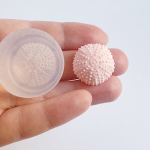 May include: A clear silicone mould for making a pink sea urchin shaped resin ornament.