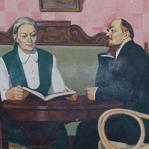 Pode incluir: Uma pintura de duas pessoas sentadas a uma mesa. A mulher à esquerda está vestindo uma camisa branca e um colete verde. Ela está segurando um livro. O homem à direita está vestindo um terno escuro e tem barba. Ele está olhando para a esquerda. A pintura é ambientada em uma sala com uma parede xadrez rosa e branca.