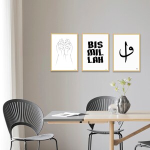 Puede incluir: Tres impresiones art&iacute;sticas enmarcadas con dise&ntilde;os minimalistas. Una impresi&oacute;n presenta un dibujo lineal de manos abiertas, otra muestra el texto "BIS MIL LAH" en letras gruesas, y la tercera muestra un s&iacute;mbolo de caligraf&iacute;a &aacute;rabe. Los marcos tienen un acabado de madera clara.