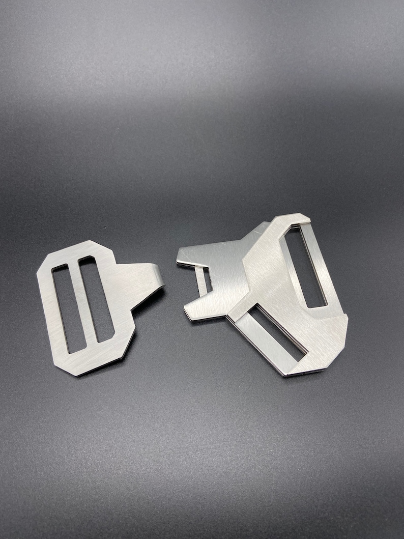 May include: Two silver metal belt buckle closures. One is a standard buckle with two slots, the other is a more complex design with a single slot.