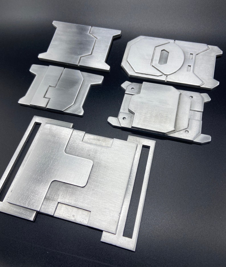K&ouml;nnte beinhalten: F&uuml;nf Metallplatten in verschiedenen Formen und Gr&ouml;&szlig;en. Die Platten sind aus geb&uuml;rstetem Metall und haben eine silberne Oberfl&auml;che.