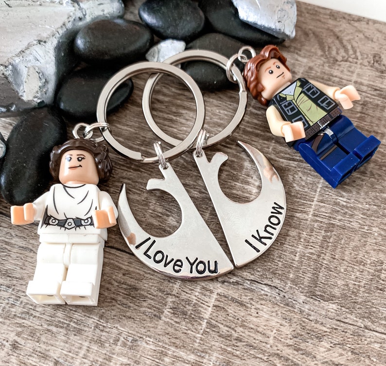 Pu&ograve; includere: Un portachiavi d'argento con due forme di mezzaluna intrecciate. Il portachiavi presenta il testo "I Love You" e "I Know" su ogni lato. Il portachiavi &egrave; attaccato a due anelli con una minifigure Lego Star Wars di Principessa Leia e Han Solo.