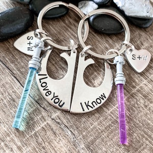 Puede incluir: Un par de llaveros plateados con un dije de sable de luz en cada uno. Los llaveros tienen la forma del s&iacute;mbolo de la Alianza Rebelde de Star Wars. Un llavero dice "Te amo" y el otro dice "Lo s&eacute;".