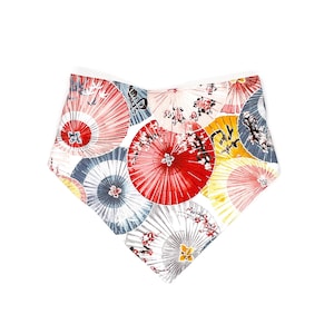 May include: A triangular bandana featuring a repeating pattern of traditional Japanese paper umbrellas in vibrant shades of red, yellow, blue, and white, accented with delicate floral motifs and intricate line details across the fabric surface.