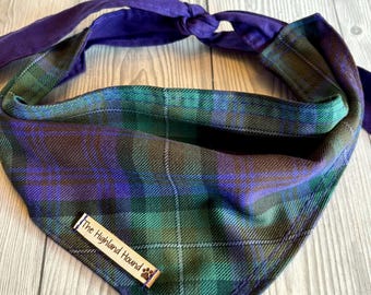 May include: A dog bandana in a tartan pattern with green, blue, and purple hues. It features a purple tie and a small wooden tag with the text "The Highland Hound".
