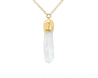 Puede incluir: Un collar de cadena de oro con un colgante de cristal de cuarzo transparente. El cristal es en bruto y tiene una tapa chapada en oro en la parte superior.