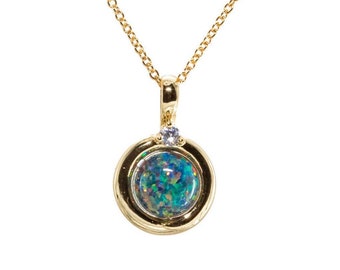 May include: A gold chain necklace with a round pendant featuring a blue-green opal surrounded by a gold bezel and a small clear gemstone.