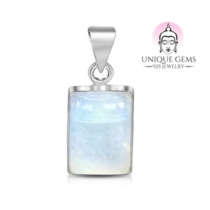 Puede incluir: Un colgante de plata con una piedra preciosa rectangular blanca iridiscente. El colgante está sobre un fondo blanco.