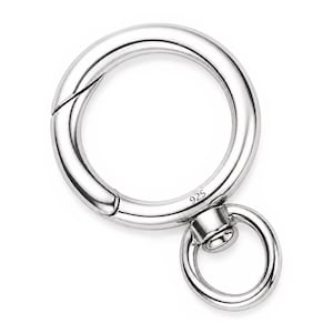 Puede incluir: Una argolla de resorte de metal plateado pulido con un diseño circular y un anillo giratorio más pequeño adjunto. El anillo principal incluye un mecanismo de apertura por resorte y tiene grabado el número 925 en su superficie lisa.