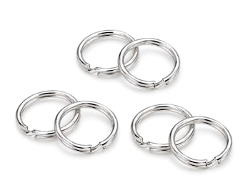 May include: A collection of six circular silver-toned metal split rings arranged in three pairs. Each ring features a double-loop coil design with a smooth, polished finish, commonly used for attaching keys or small items to keychains or hardware.