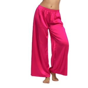 Könnte beinhalten: Helle pinkfarbene Palazzo-Hose mit weitem Bein. Die Hose ist aus einem glänzenden, seidigen Material gefertigt und hat einen elastischen Bund. Die Hose ist einfarbig und wird vor weißem Hintergrund gezeigt.