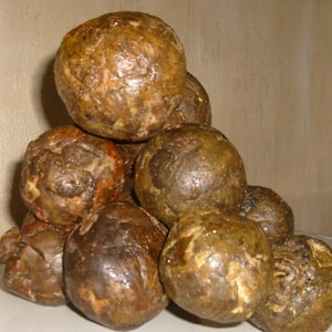 Puede incluir: Un montón de ocho objetos redondos, texturizados, orgánicos de color marrón. Los objetos están dispuestos en forma de pirámide.