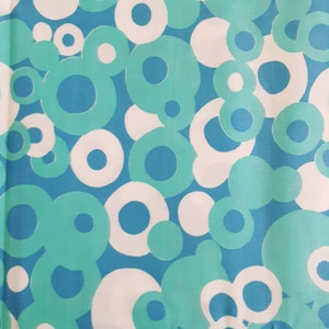 May include: A fabric with a repeating pattern of white and turquoise circles on a light blue background.