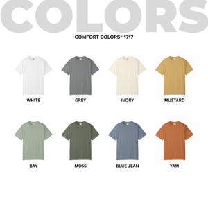 May include: A display of eight Comfort Colors 1717 t-shirts in various colors, including white, grey, ivory, mustard, bay, moss, blue jean, and yam. The word "COLORS" is at the top, with each shirt labeled with its color name.
