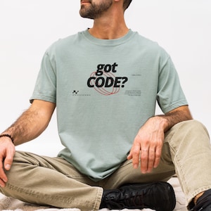Model wearing a bay Comfort Colors 1717 T-shirt with a retro-tech GOT CODE? graphic featuring bold black typography, red orbital linework, and small technical details.
