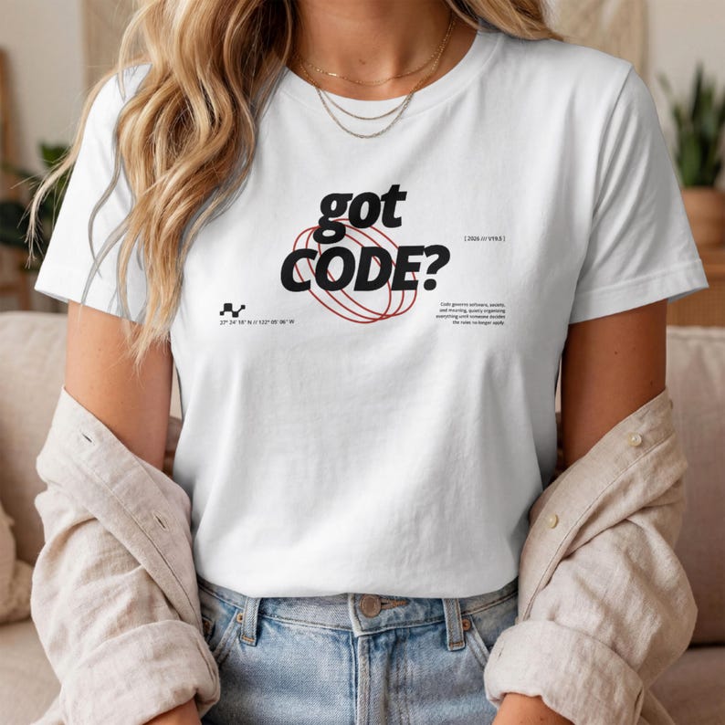 Model wearing a white Comfort Colors 1717 T-shirt with a retro-tech GOT CODE? graphic featuring bold black typography, red orbital linework, and small technical details.