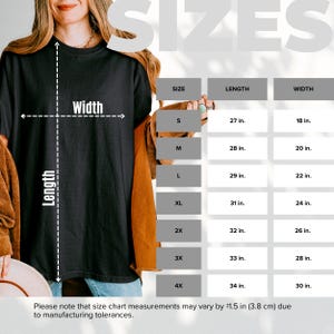 Może przedstawiać: Tabela rozmiar&oacute;w czarnego t-shirtu przedstawiająca długość i szerokość w calach dla rozmiar&oacute;w od S do 4X. Tabela zawiera długości od 27 do 34 cali oraz szerokości od 18 do 30 cali, z uwzględnieniem tolerancji produkcyjnej wynoszącej 3,8 cm.