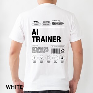 Model is wearing a white t-shirt shown from the back, displaying an AI Trainer parody label graphic designed like a tech product spec sheet with alignment indicators, ingredients, and dry humor.