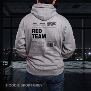May include: A gray hoodie with the text "RED TEAM" in large, bold letters on the back. Additional text includes "100% OFFENSE MODE" and "EXPERTISE PEN TESTING". The hoodie has a drawstring hood and a kangaroo pocket. The bottom of the hoodie reads "HOODIE SPORT GREY".