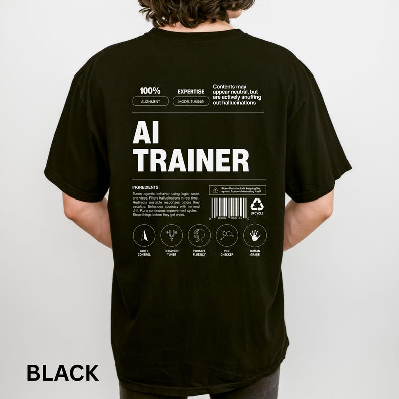 Model is wearing a black t-shirt shown from the back, displaying an AI Trainer parody label graphic designed like a tech product spec sheet with alignment indicators, ingredients, and dry humor.