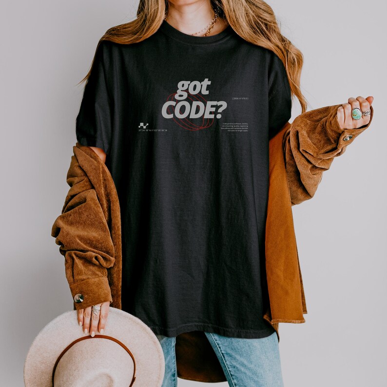 Model wearing a black Comfort Colors 1717 T-shirt with a retro-tech GOT CODE? graphic featuring bold black typography, red orbital linework, and small technical details.
