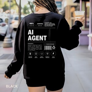 May include: Black sweatshirt with the text "AI AGENT" in white. The back of the sweatshirt features additional text and graphics, including "100% HUMAN-LIKE" and "EXPERTISE NEURAL NET". The sweatshirt has a crew neck and long sleeves.