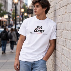 Model wearing a white Comfort Colors 1717 T-shirt with a retro-tech GOT CODE? graphic featuring bold black typography, red orbital linework, and small technical details.