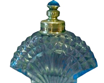 Könnte beinhalten: Eine transparente Glasparfümflasche mit fächerförmigem Körper und einem Deckel aus messingfarbenem Metall. Die Flasche hat ein rautenförmiges Muster und einen blauen Glasverschluss. Das Design erinnert an Vintage-Parfümflaschen.