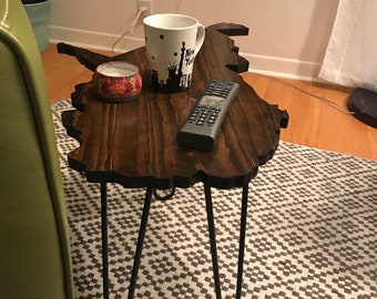 May include: A dark brown wooden table shaped like the state of New York, with black hairpin legs. A white mug with a black design of the New York City skyline and the words "New York" is on the table, along with a small candle in a glass jar.